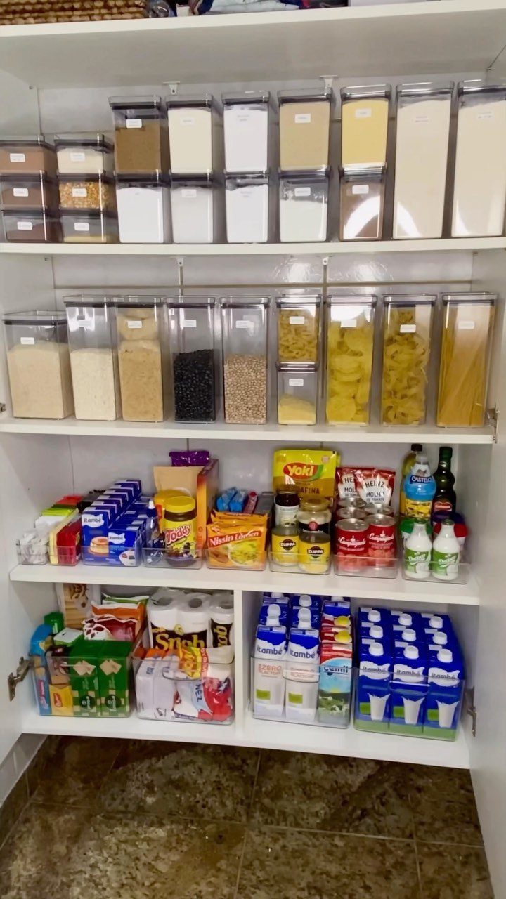 White kitchen pantry shelves organized with clear containers and various packaged food items.