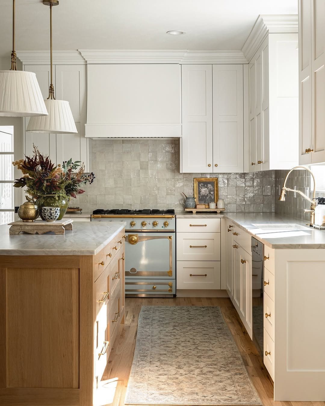 White kitchen with a grey zellige tile backsplash and a light wood island.
