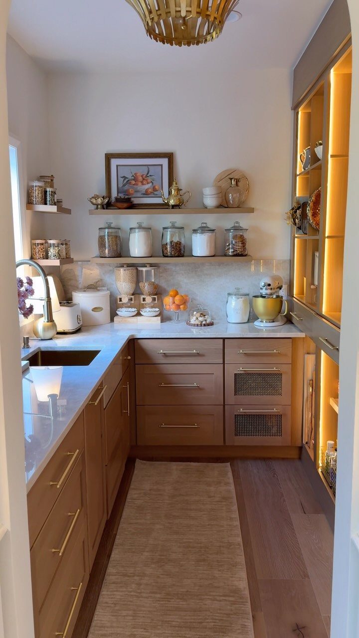 Light brown wood kitchen cabinets with white countertops and open shelving with glass jars.