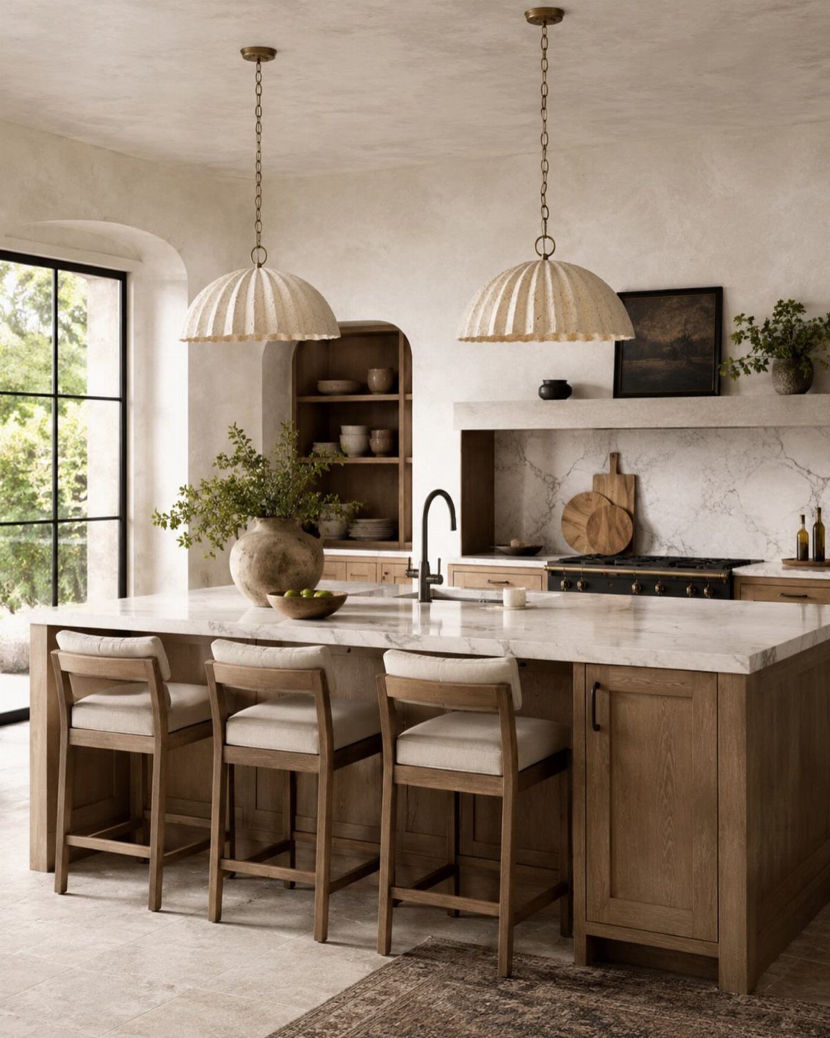 Two oversized cream ribbed dome pendant lights hanging over a marble kitchen island.