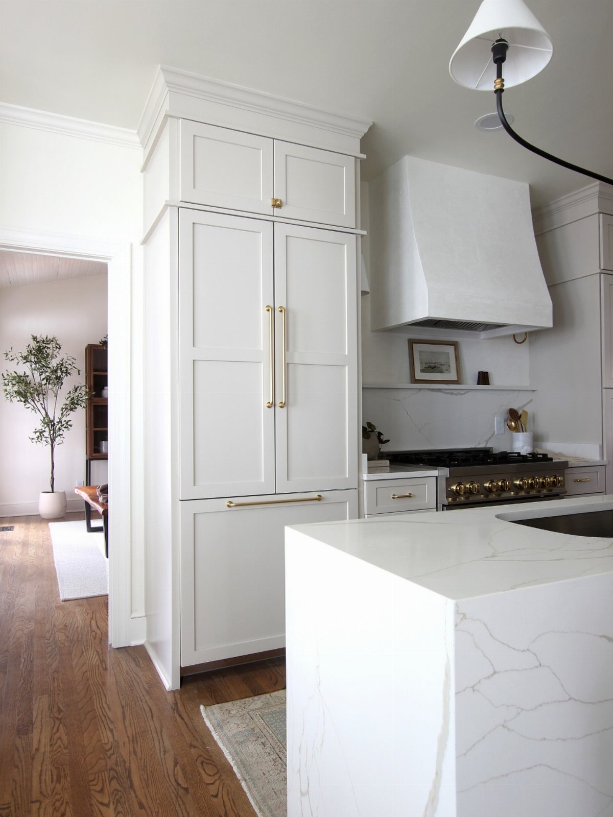 Panel-ready white refrigerator blending into cabinetry in a bright, modern white kitchen.