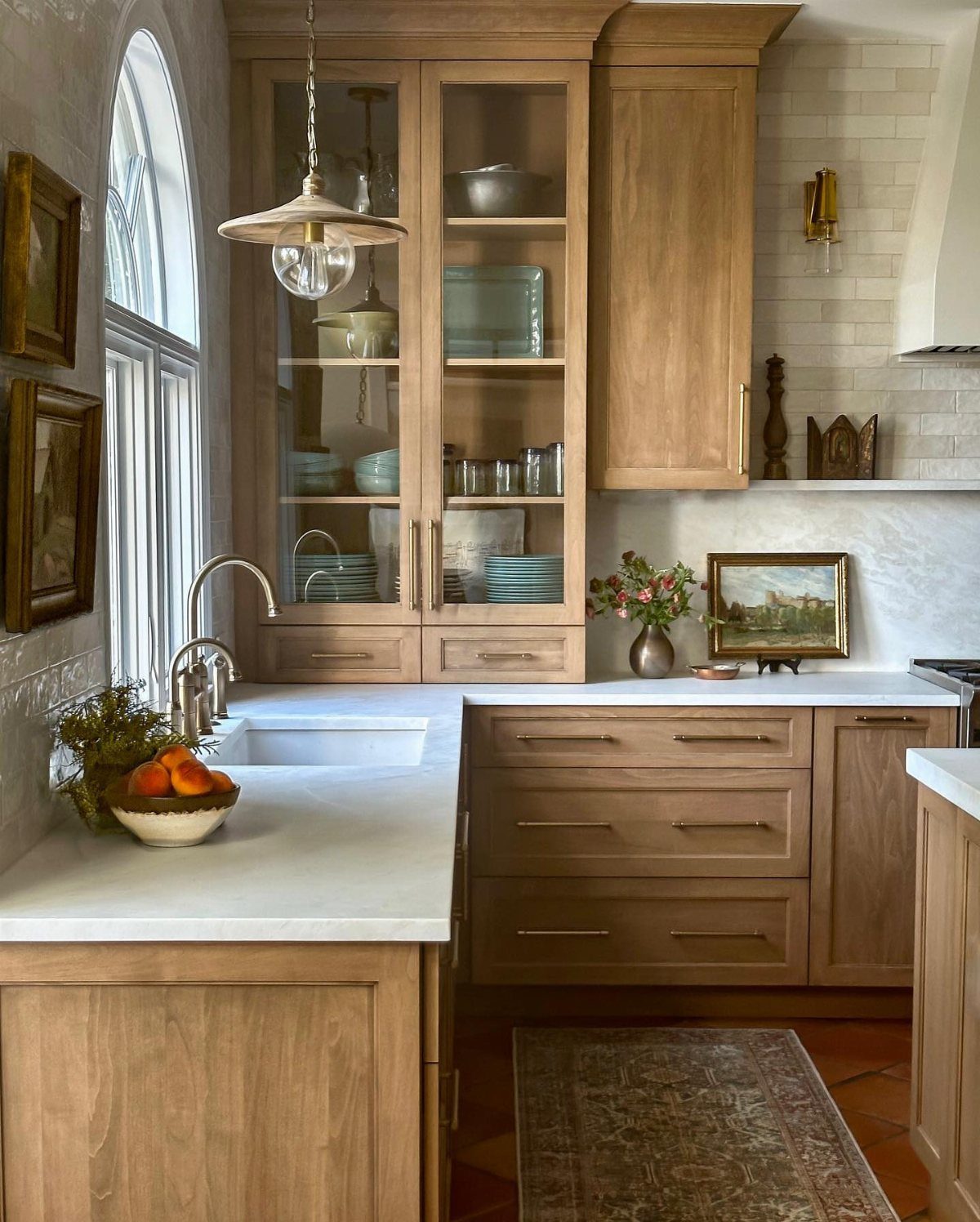 Light brown wood cabinetry with visible grain in a bright, traditional kitchen setting.