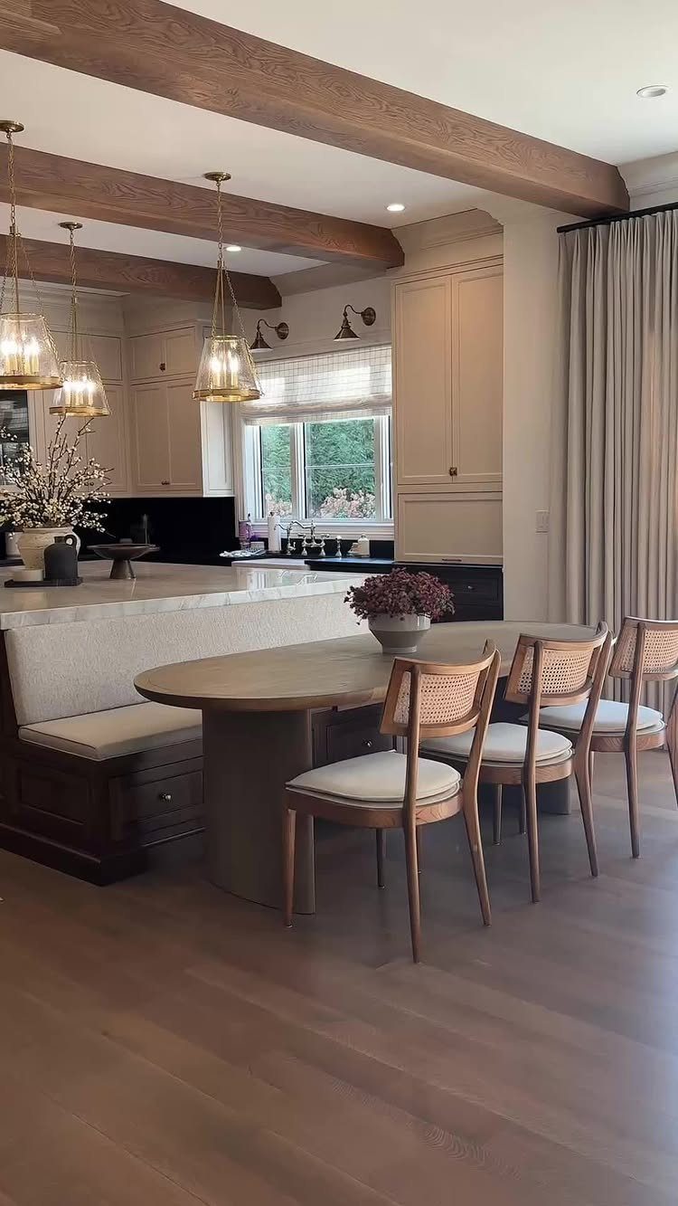 Banquette seating with white cushions and an oval wooden table in a kitchen.