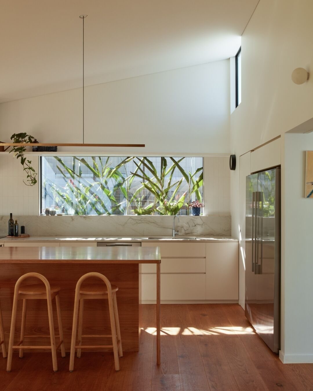 Light wood kitchen half island with two stools in a bright modern kitchen