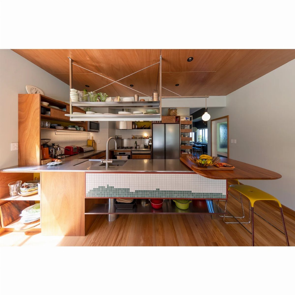 Kitchen half island with stainless steel top and attached wooden breakfast bar.