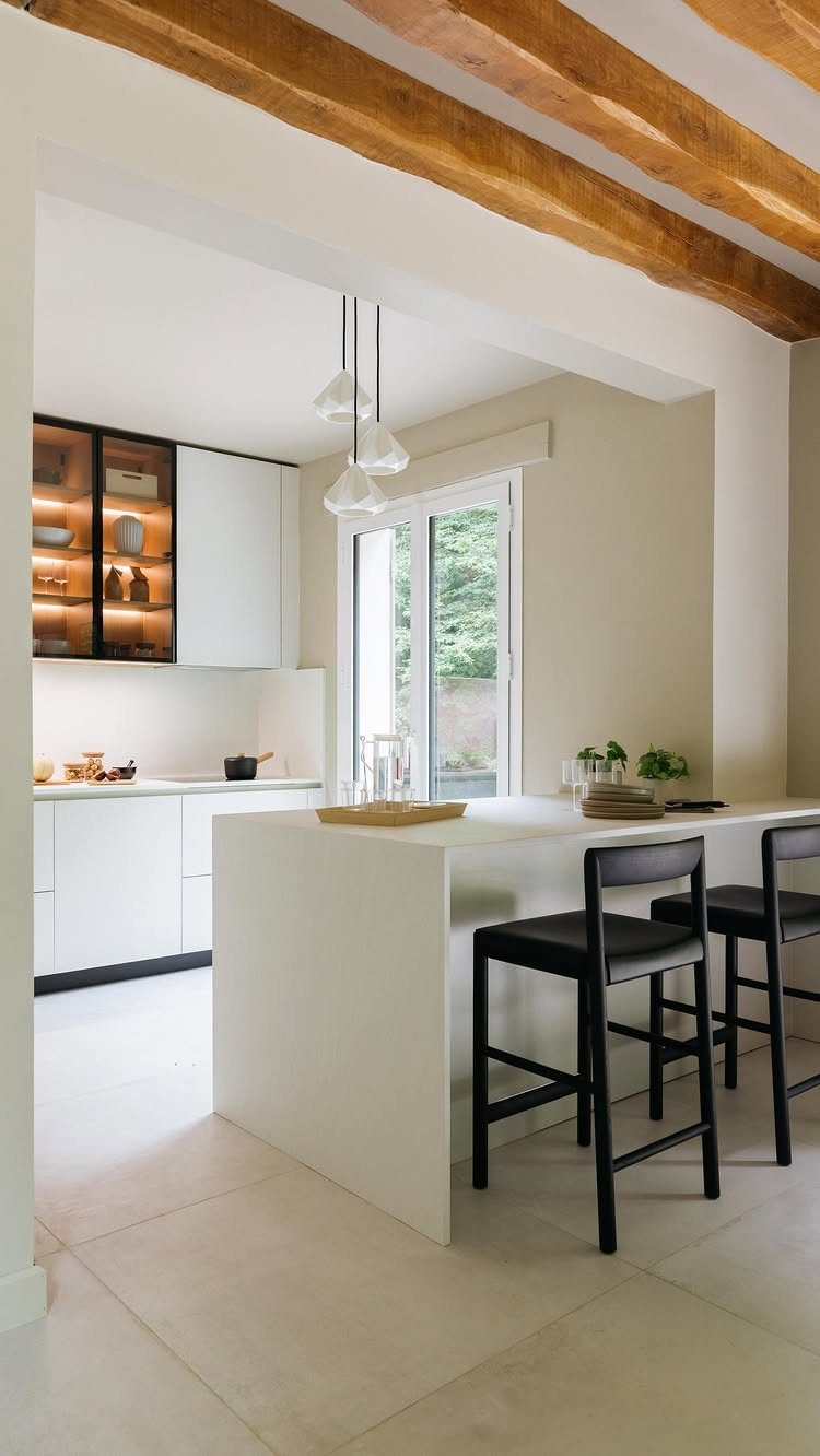 White kitchen peninsula with waterfall edge and two black modern bar stools.