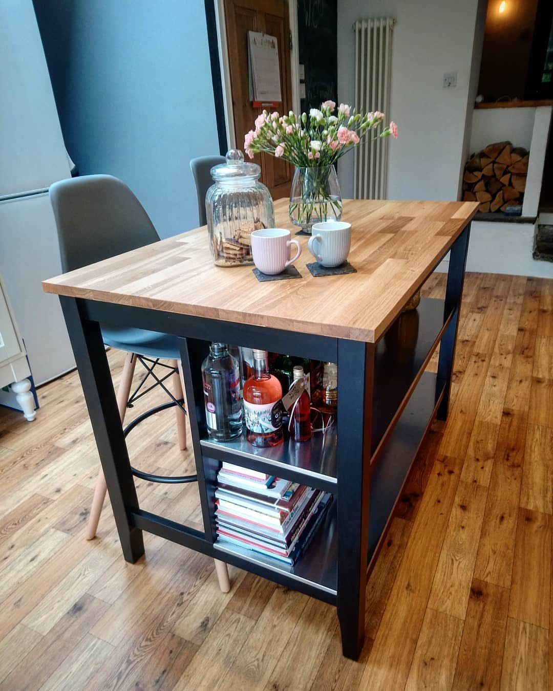Kitchen island with a wooden top and black metal frame on wood flooring.