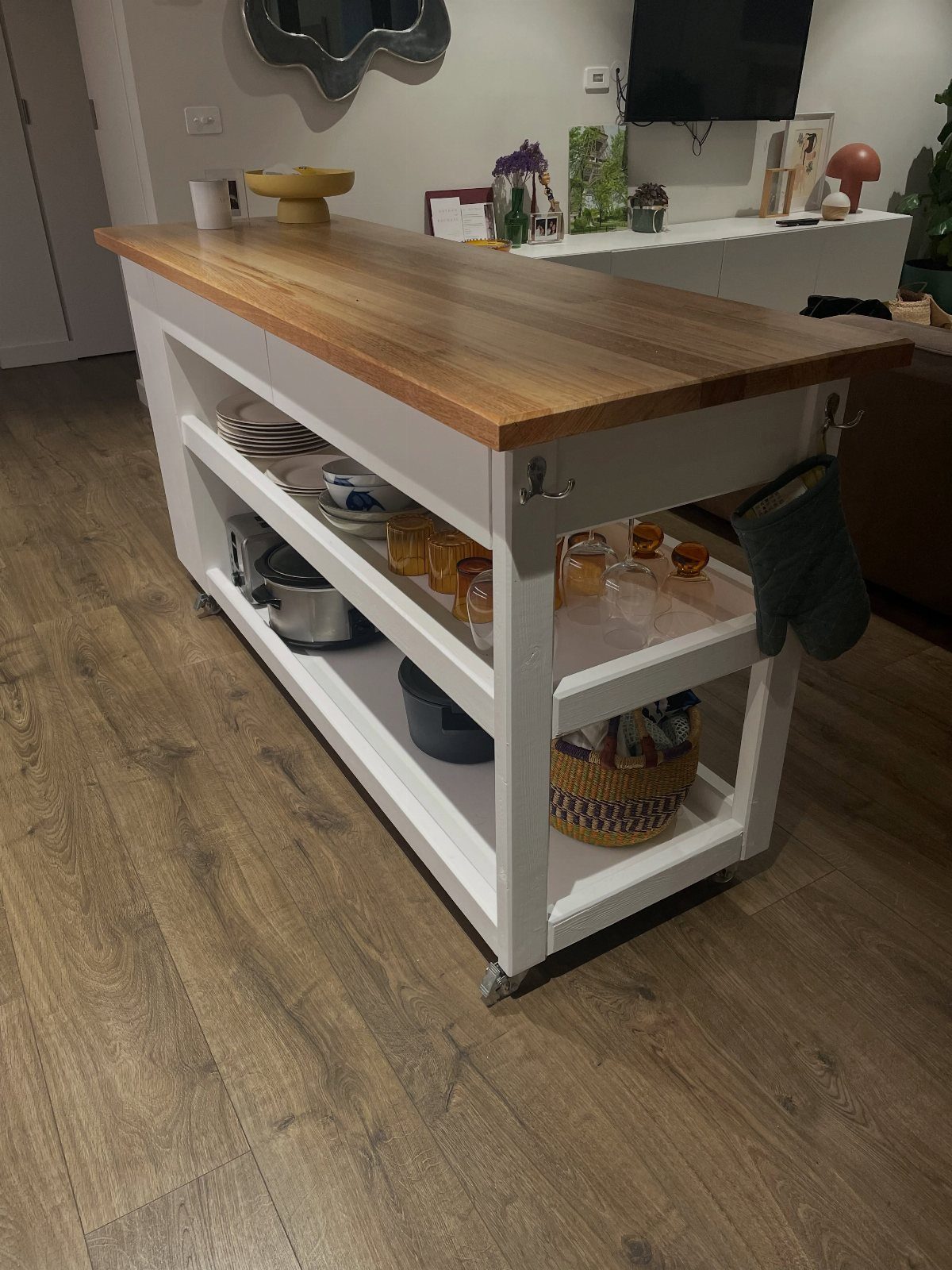 White rolling kitchen cart with a wooden butcher block top and open shelving.