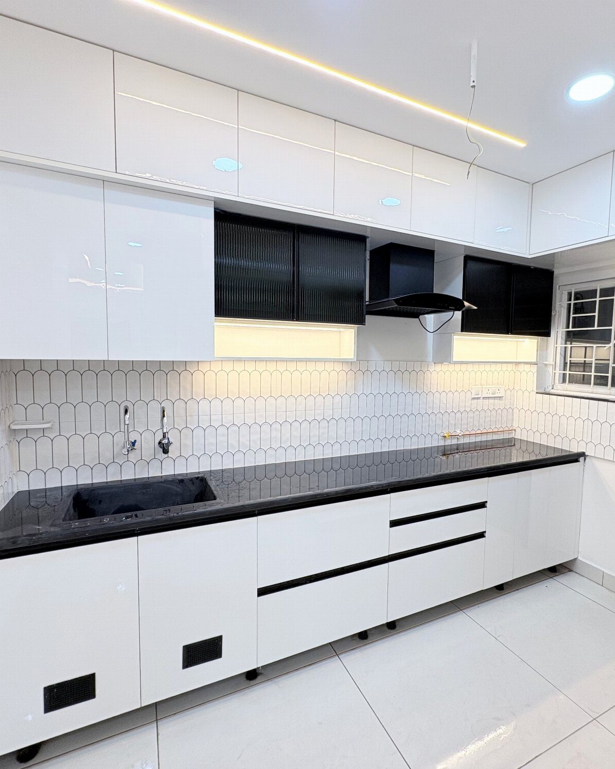 White Cabinets: 13 Kitchen Remodel Ideas 9 Modern kitchen with glossy white cabinets, black countertops, and a geometric white backsplash.