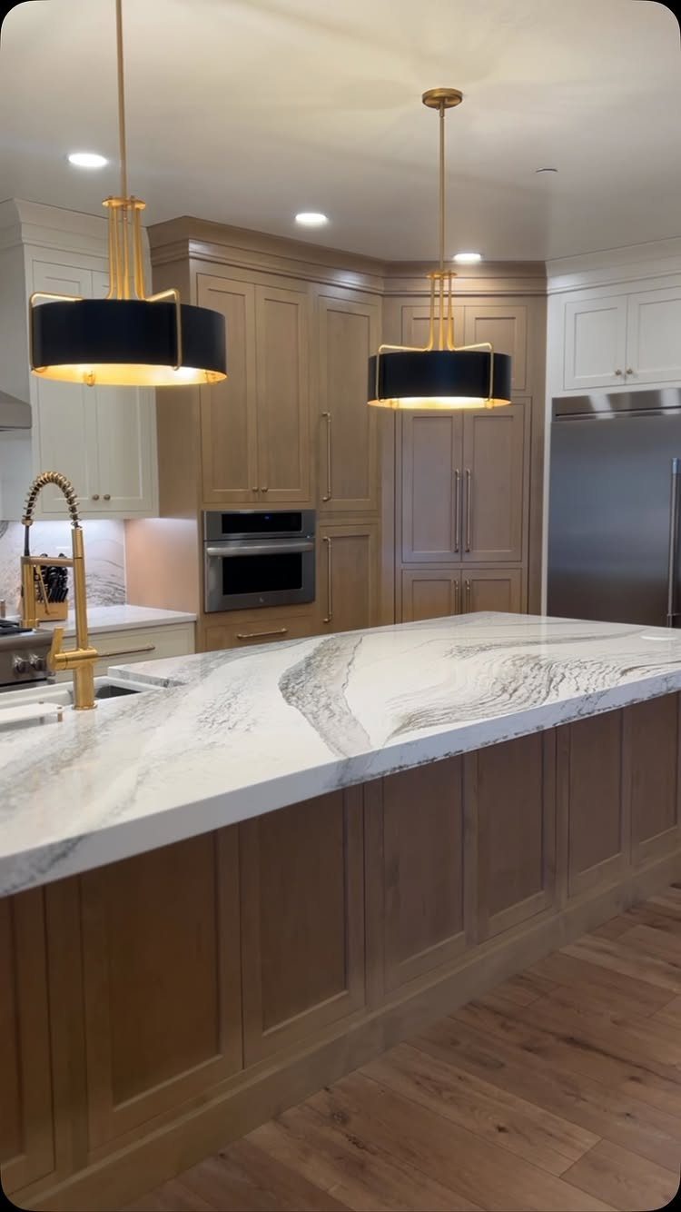 White Cabinets: 13 Kitchen Remodel Ideas 14 Modern kitchen island with white marble countertop, gold fixtures, and light wood cabinets.