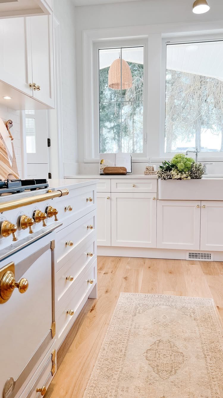 White Cabinets: 13 Kitchen Remodel Ideas 6 White shaker cabinets with gold hardware and light hardwood floors in a bright kitchen