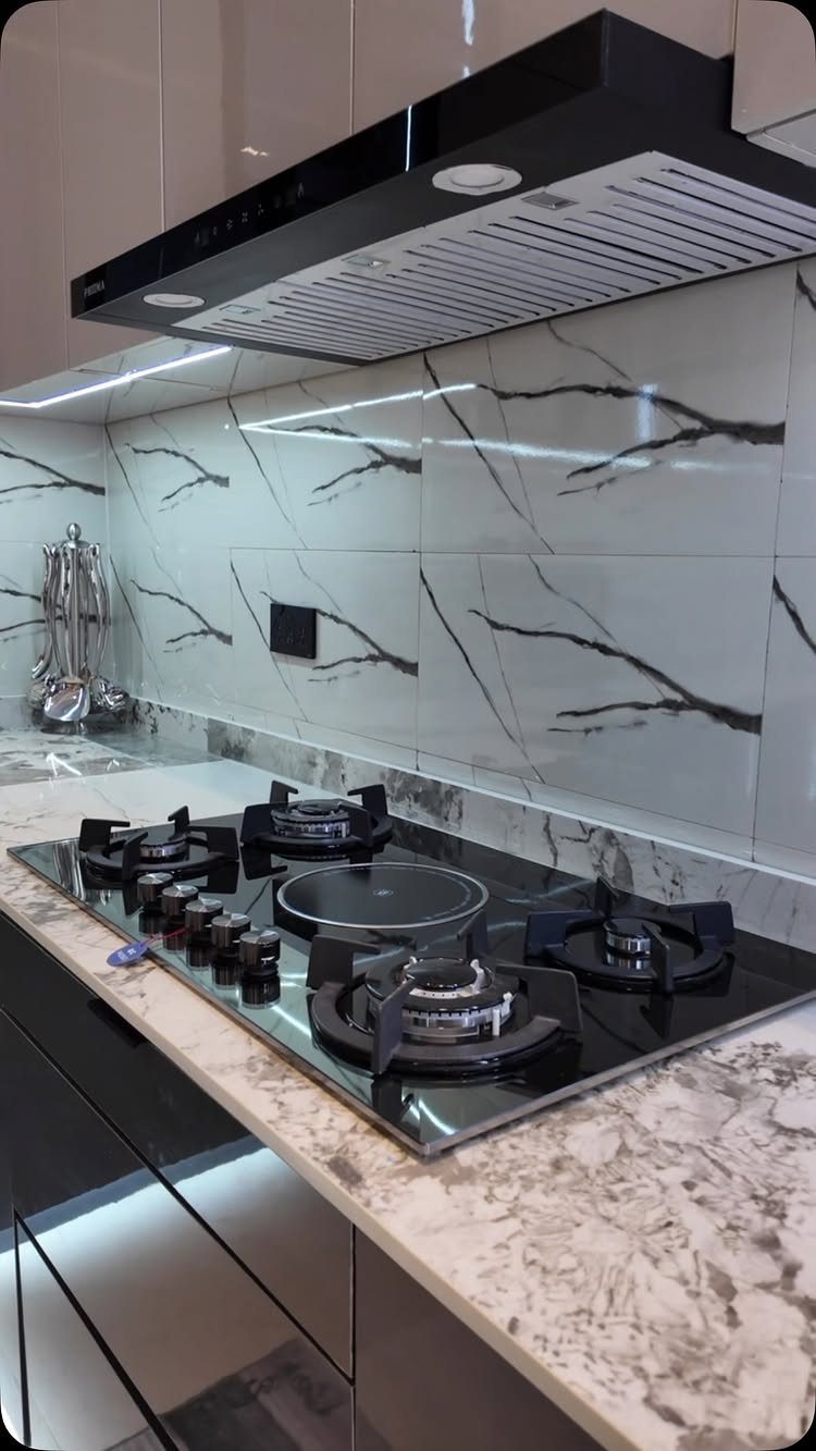 17 Kitchen Stoves Ideas for Every Style and Cooking Need 17 Modern black gas stovetop built into a white marble kitchen countertop with range hood.