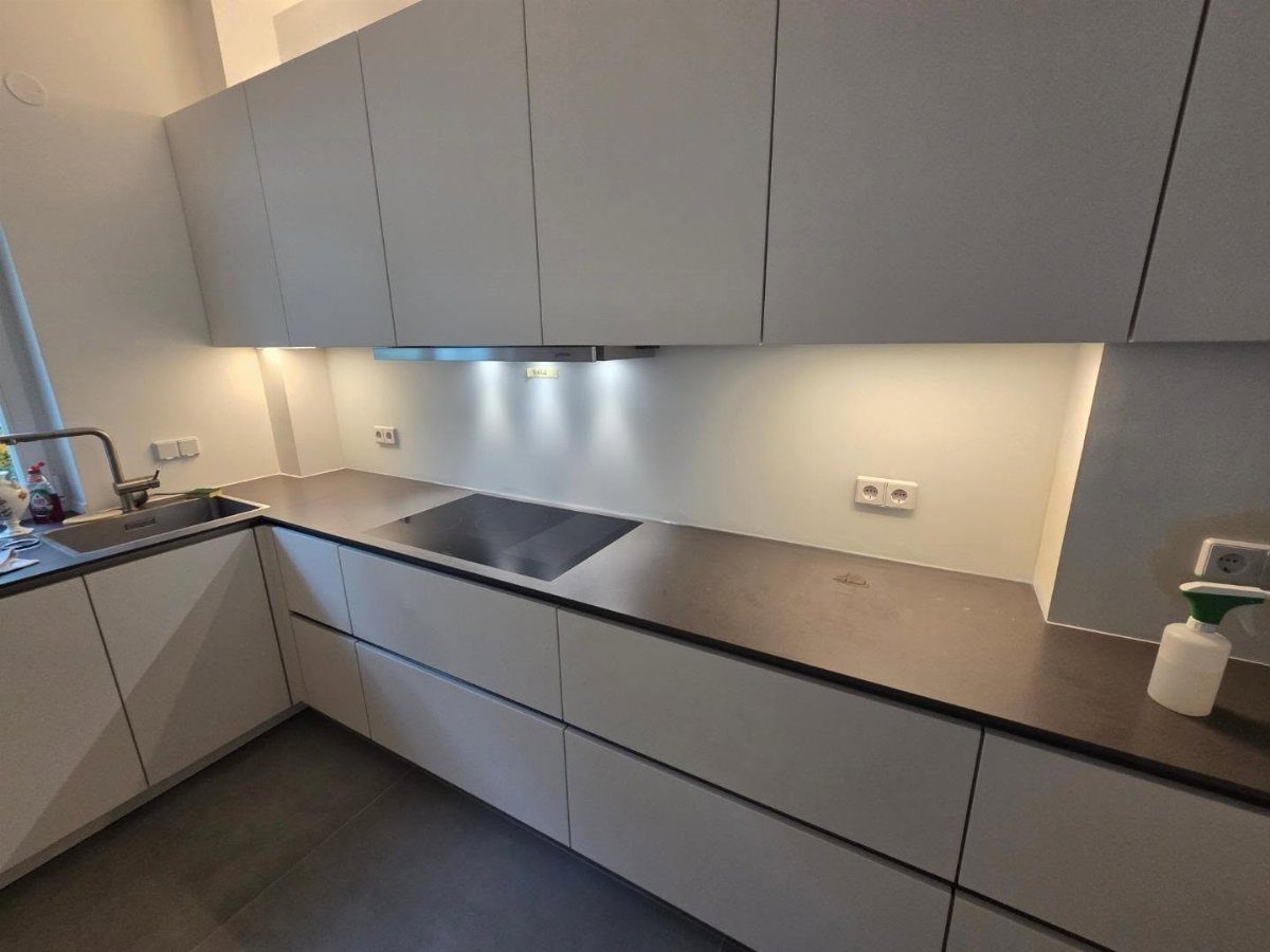 17 Kitchen Stoves Ideas for Every Style and Cooking Need 4 Modern kitchen with light gray cabinets, dark countertops, and a black induction cooktop.