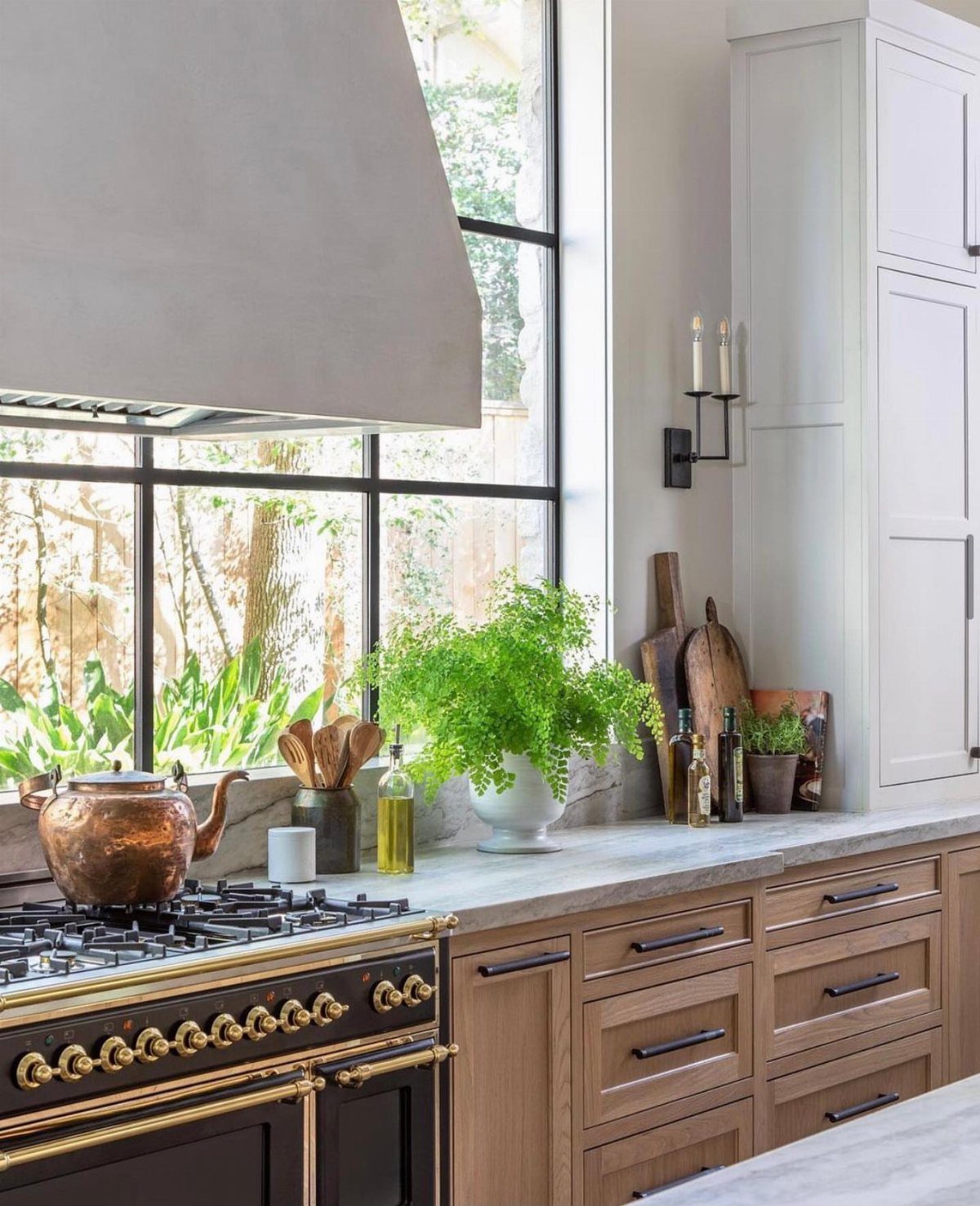 17 Kitchen Stoves Ideas for Every Style and Cooking Need 6 Black gas range with gold knobs positioned in front of a large window.