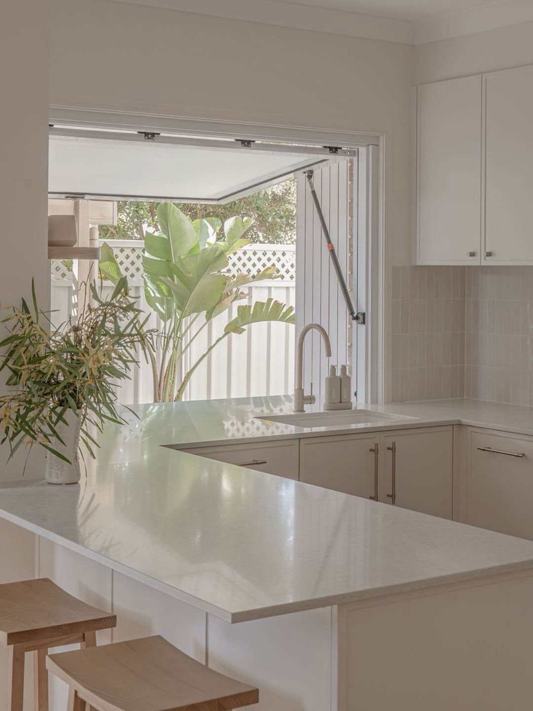 Modern white kitchen with an open awning window located above the sink.