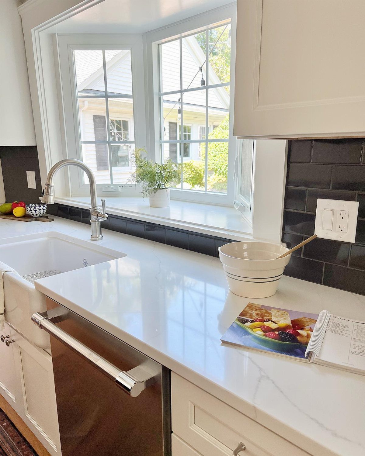 Bay window in a white kitchen with a plant on the ledge above a sink.