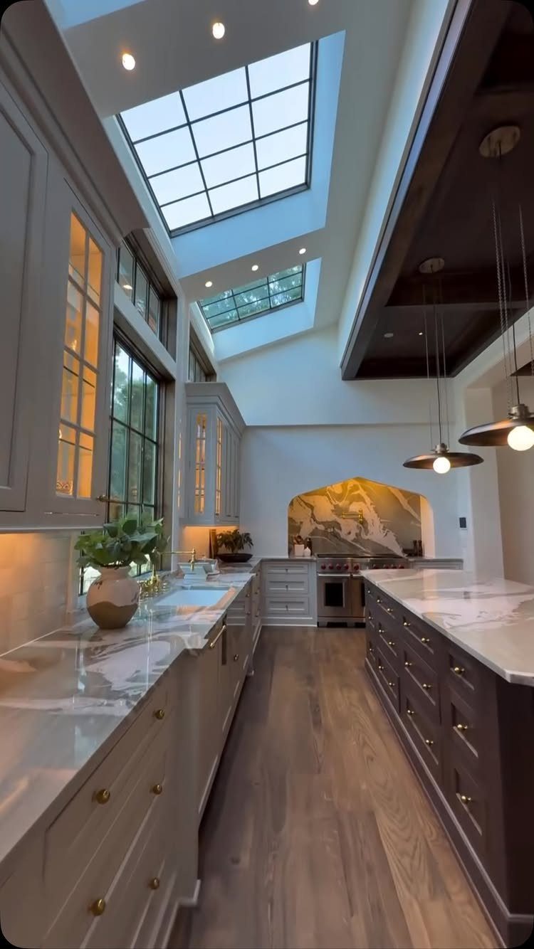 Two grid-patterned skylights in a modern kitchen ceiling with grey cabinets and marble counters.