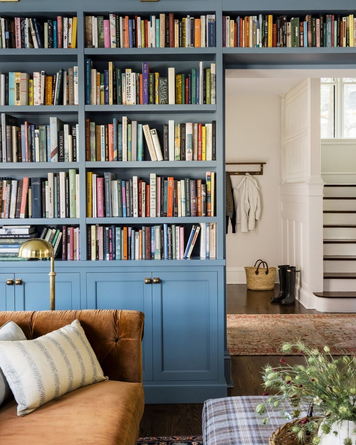 Blue floor-to-ceiling built-in bookshelves filled with books next to a brown leather sofa.
