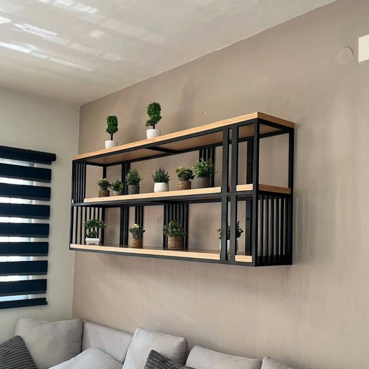 Black metal and wood wall shelves holding various small potted green plants.