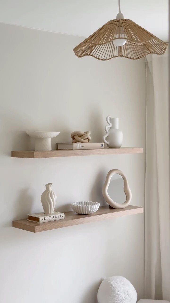Two light-wood floating shelves styled with white ceramic vases, bowls, and a mirror.