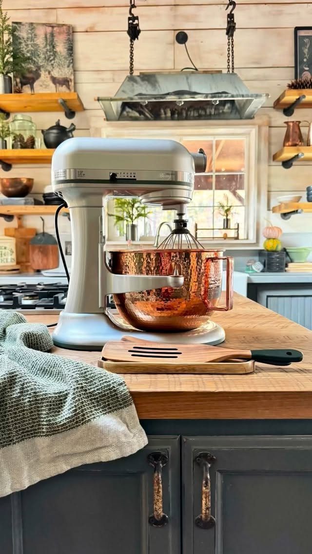 Cream matte stand mixer with a hammered copper bowl on a wooden countertop.
