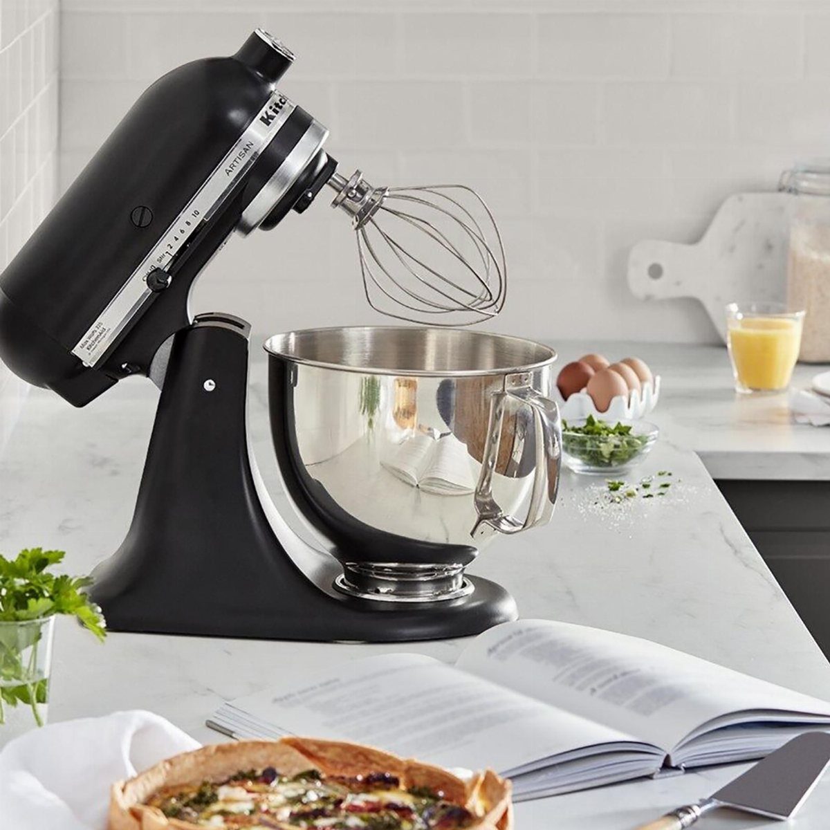 Matte black stand mixer with whisk and bowl on a white marble countertop