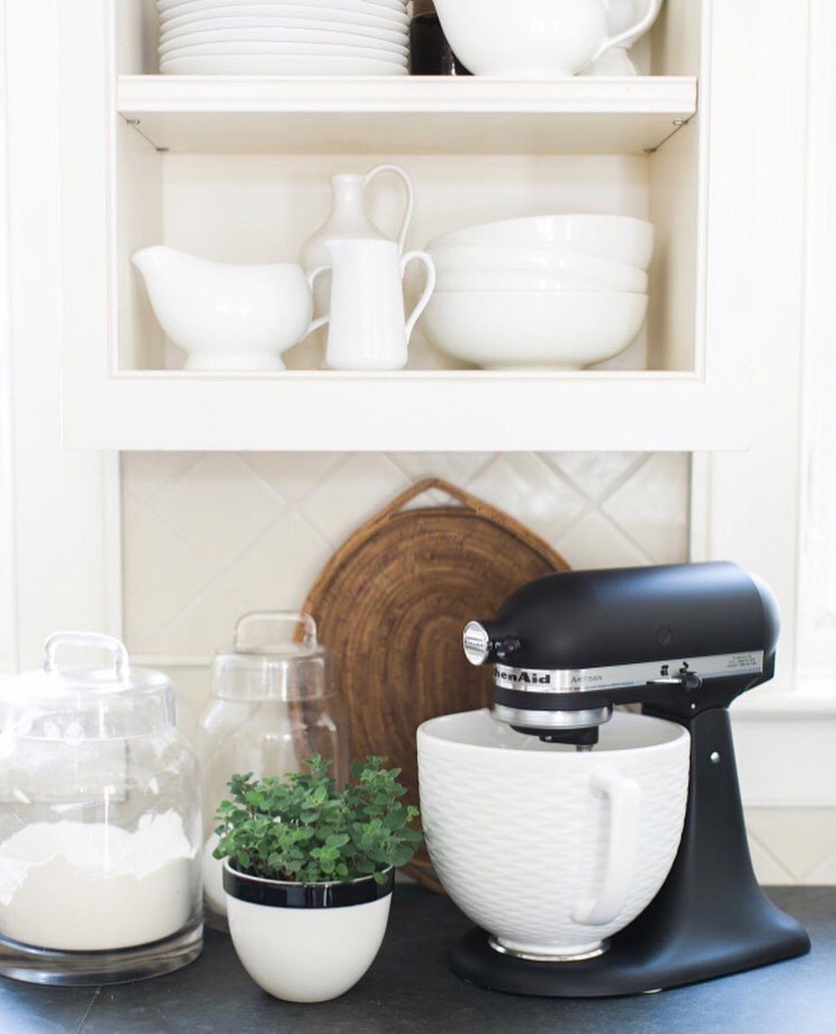 Matte black KitchenAid mixer with a white ribbed ceramic bowl on a dark counter.