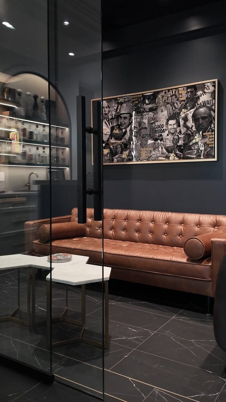 13 Mini Bar House Design Ideas to Fit Your Space and Taste 13 Brown tufted leather sofa in a dark lounge with a background bar area.
