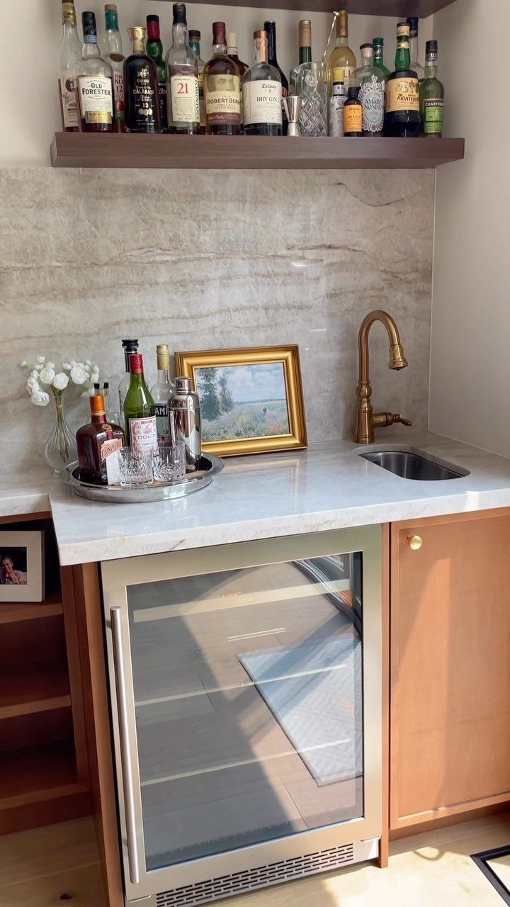 13 Mini Bar House Design Ideas to Fit Your Space and Taste 9 Small home bar with marble countertop, gold sink, beverage cooler, and liquor shelf.