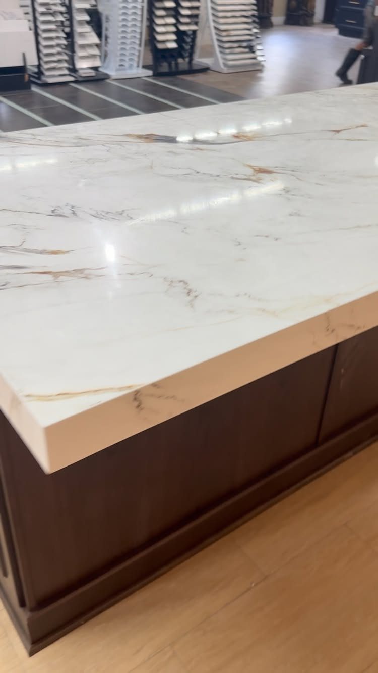 White quartz countertop with gold veining on dark brown wooden kitchen cabinets.
