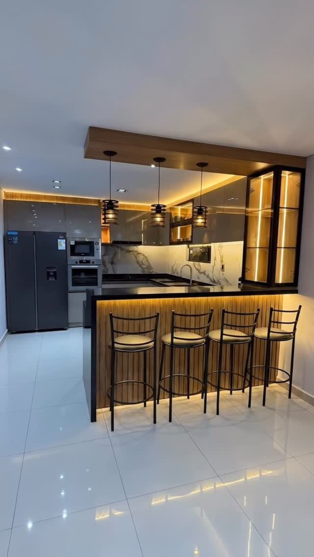 Modern kitchen island with four black bar stools and warm pendant lighting.