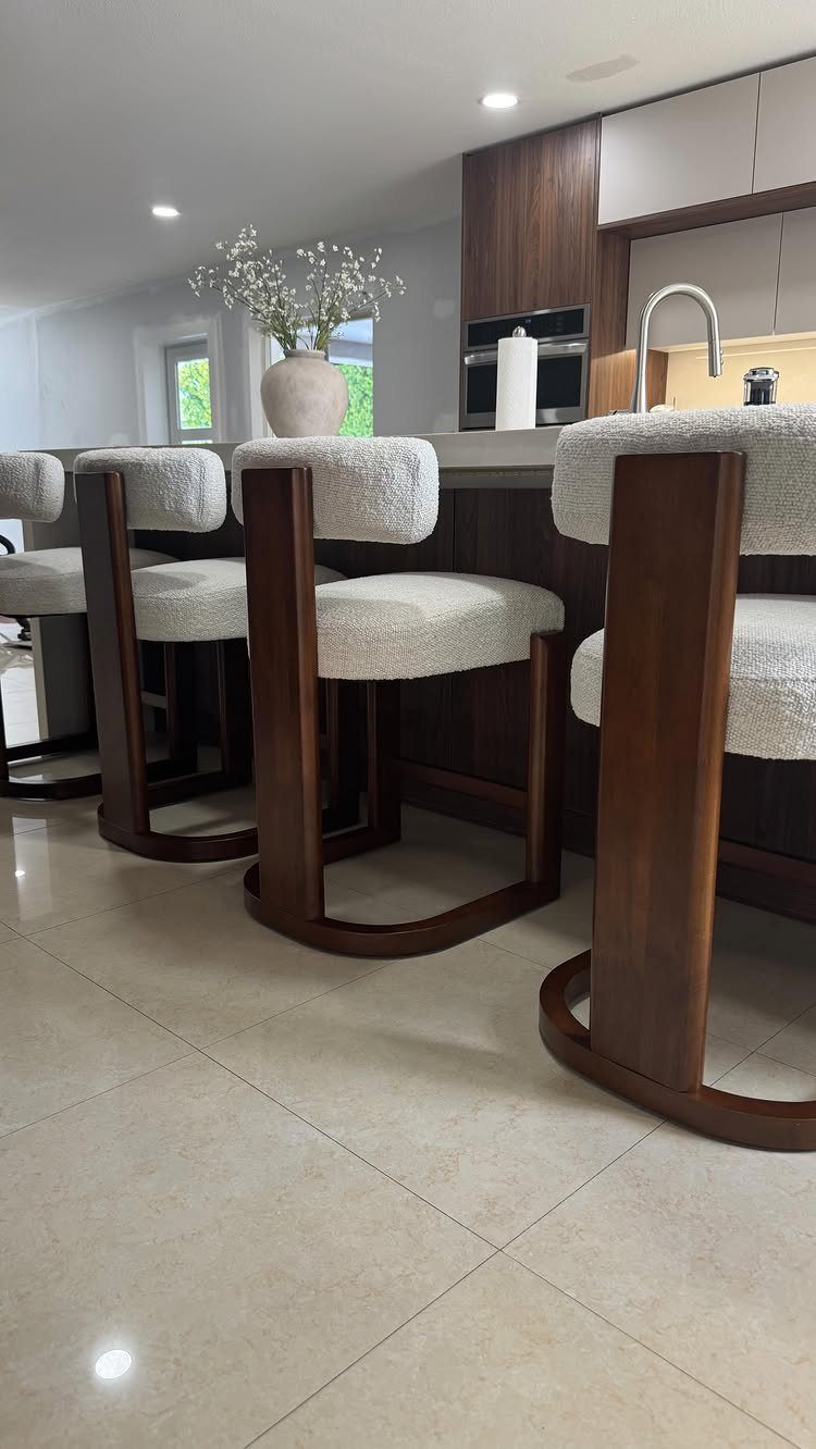 White bouclé counter stools with curved dark wood frames at a kitchen island.