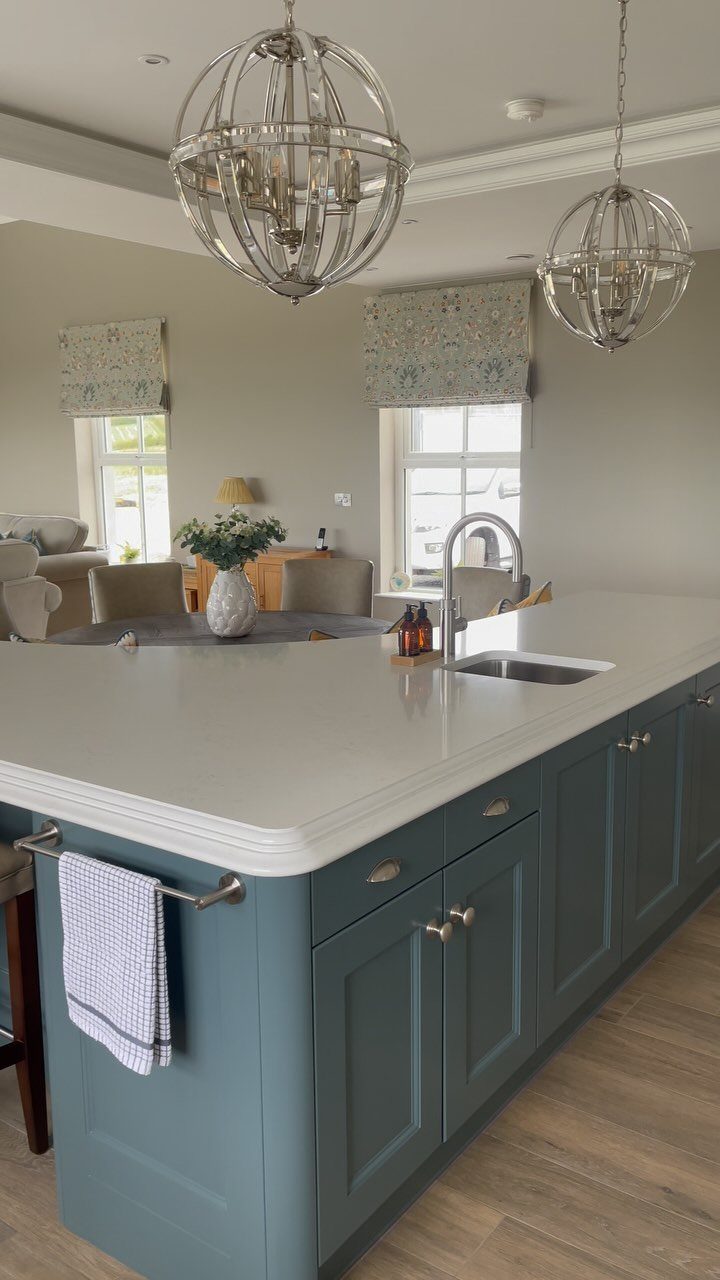 Blue kitchen island with white countertop, built-in sink, and spherical chrome pendant lights.