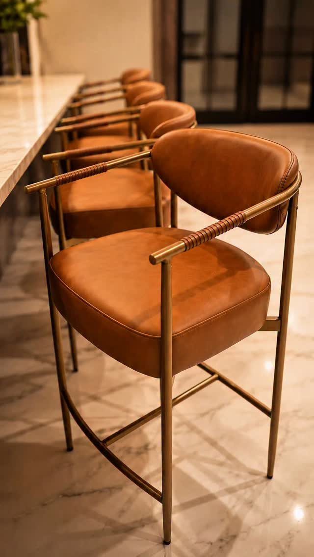 Brown leather armchairs with gold frames lined up along a white marble counter.