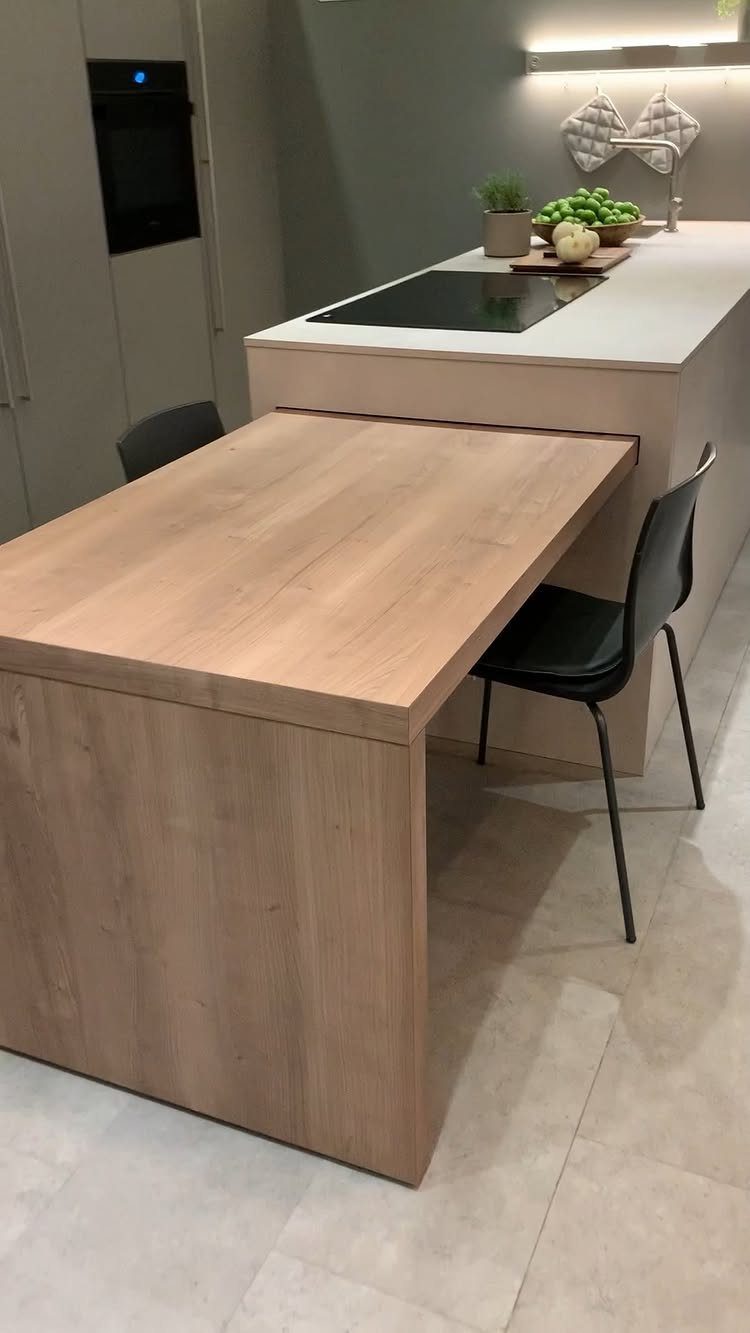 Light wood table extension attached to a white modern kitchen island with black chairs.