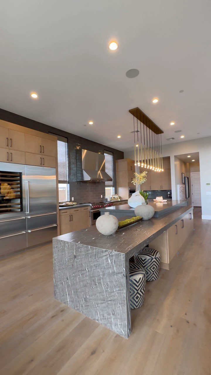 Two-level kitchen island with grey stone waterfall edge and patterned stools in modern kitchen.