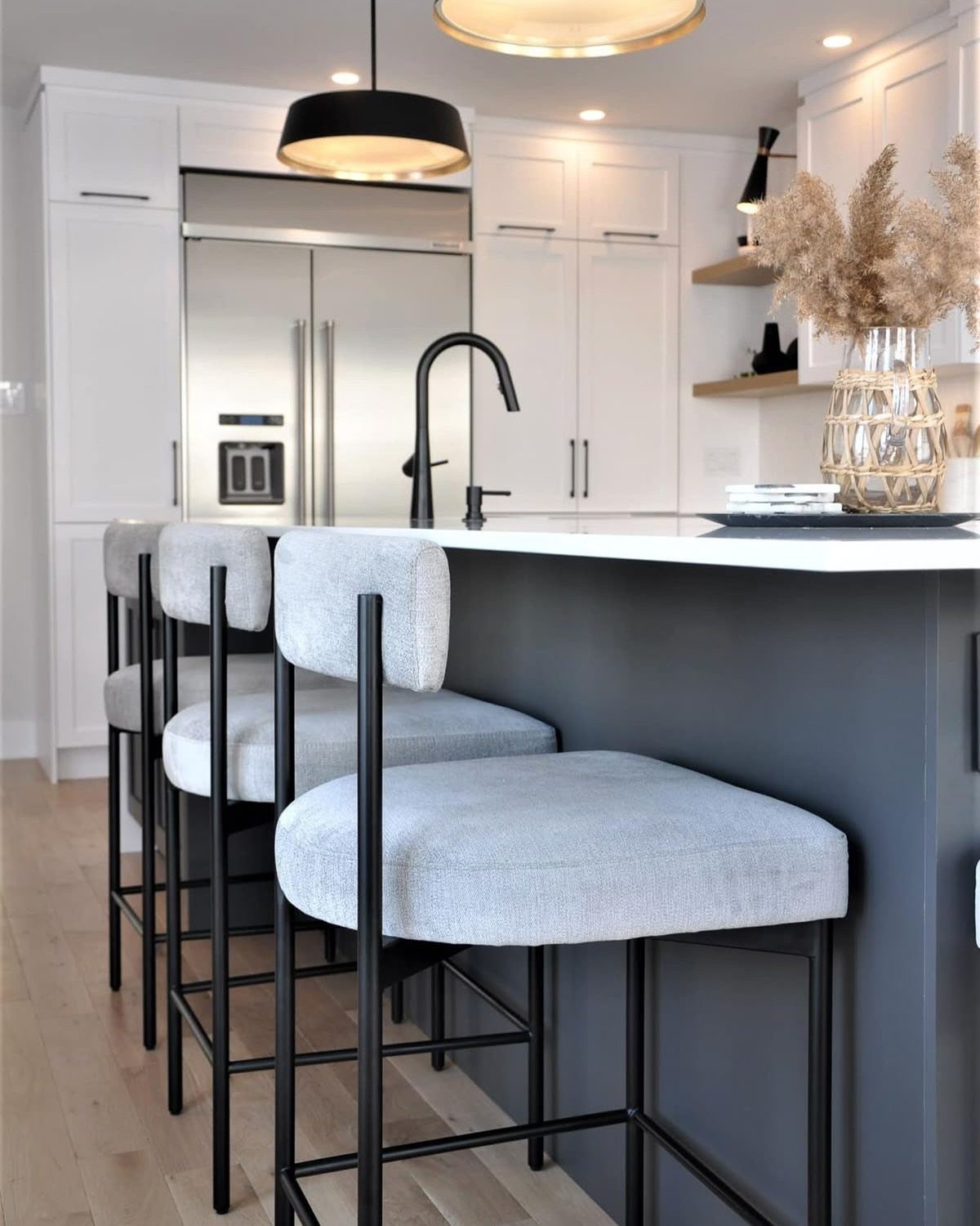 Dark grey kitchen island with white countertop and three light grey bar stools.