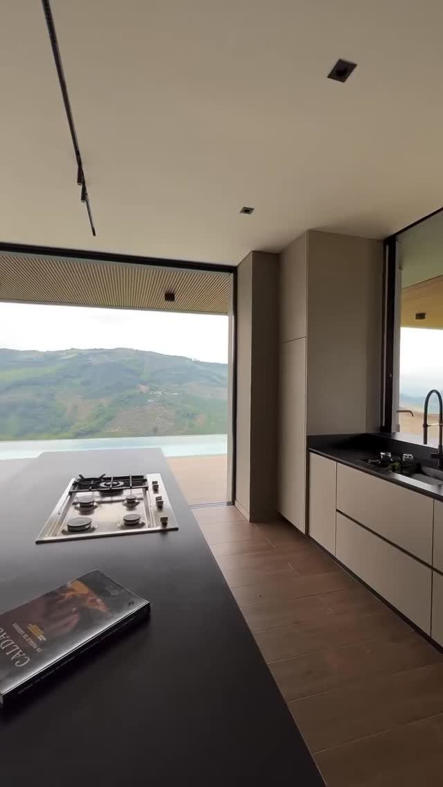 15 Modern Minimalist Home Ideas That Define Clean Living 4 Modern kitchen with a large floor-to-ceiling window overlooking a green mountain landscape.