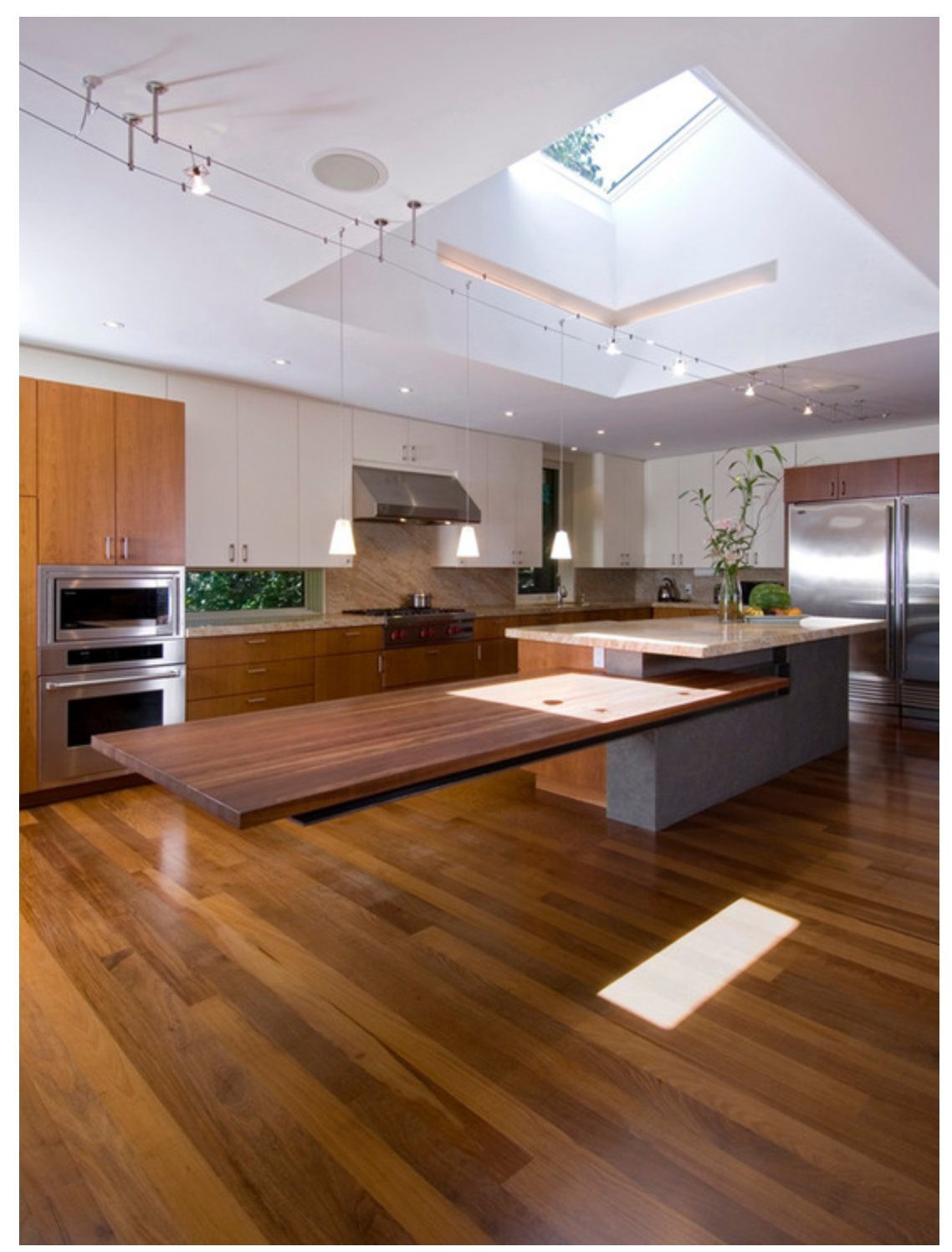 Grey kitchen island with a large dark wood dining table attached to the side.