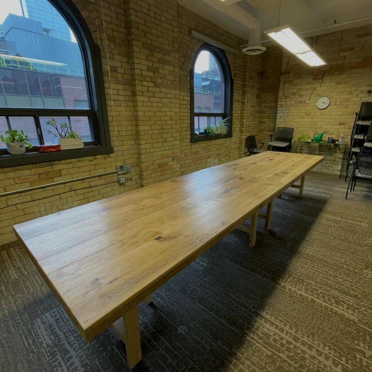 Long reclaimed wood conference table in an office with exposed brick walls.