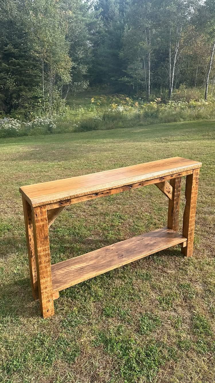Rustic reclaimed wood console table with two shelves standing on a grassy lawn.