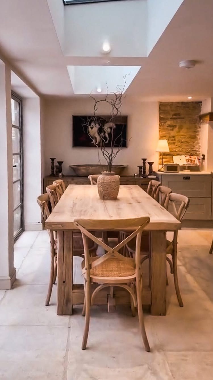Wooden dining table and matching cross-back chairs in a bright, modern dining room.