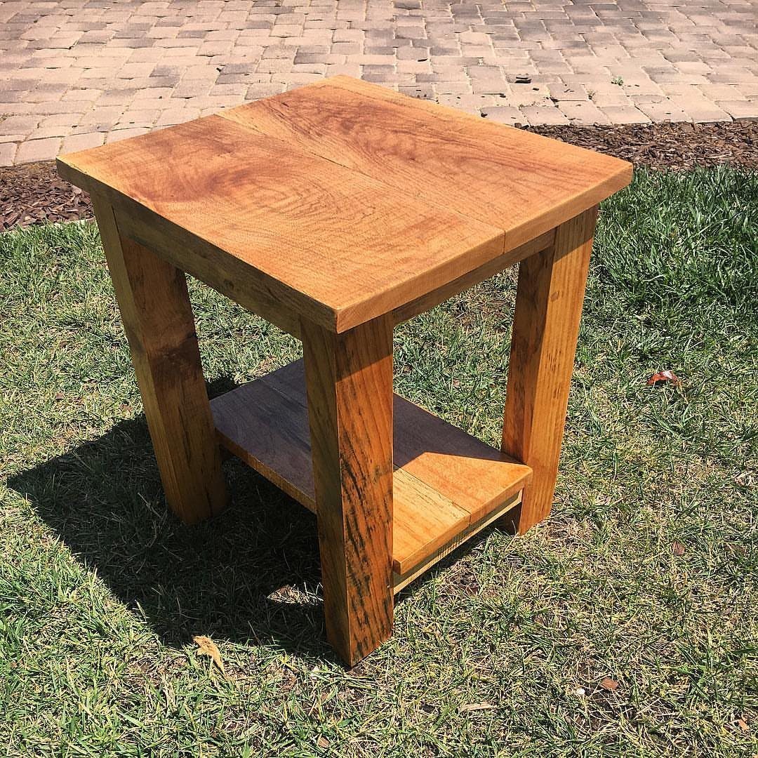 Small square reclaimed wood end table with a lower shelf on green grass.