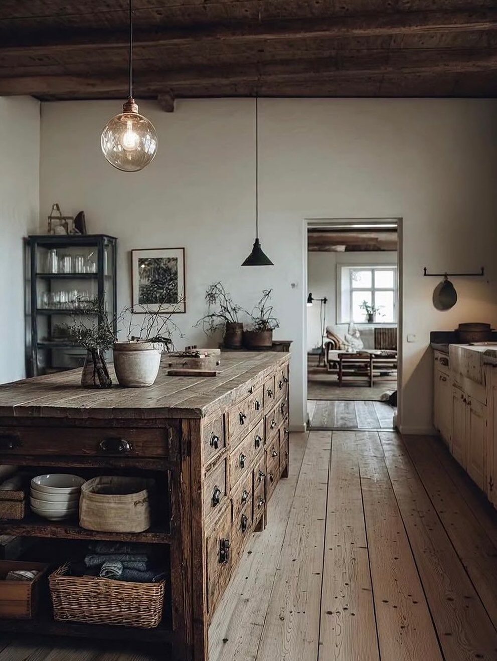 Rustic reclaimed wood kitchen island with drawers and baskets in a farmhouse kitchen.