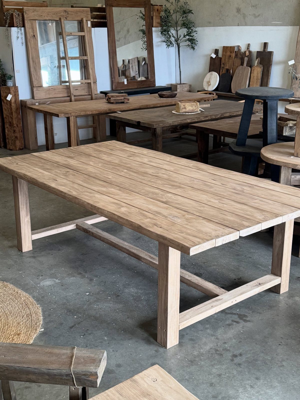 Rustic reclaimed wood dining table with a thick plank top in a furniture showroom.