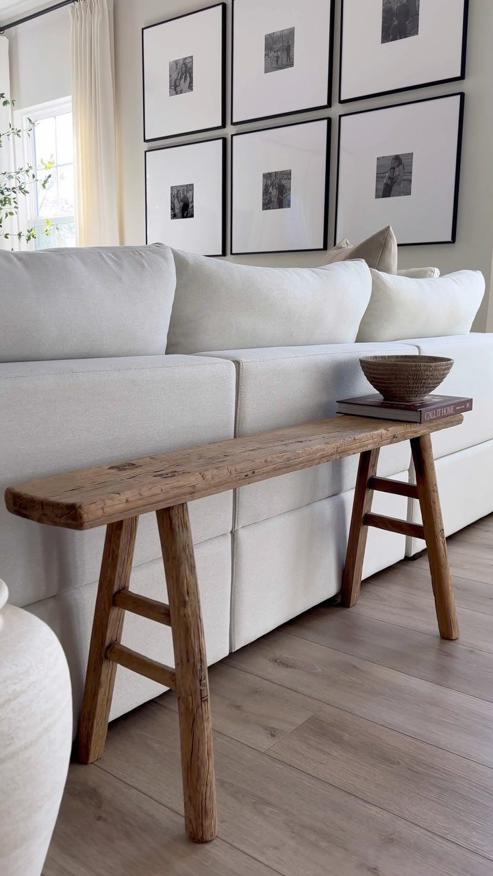 Rustic reclaimed wood bench in front of a white modular sofa and gallery wall.