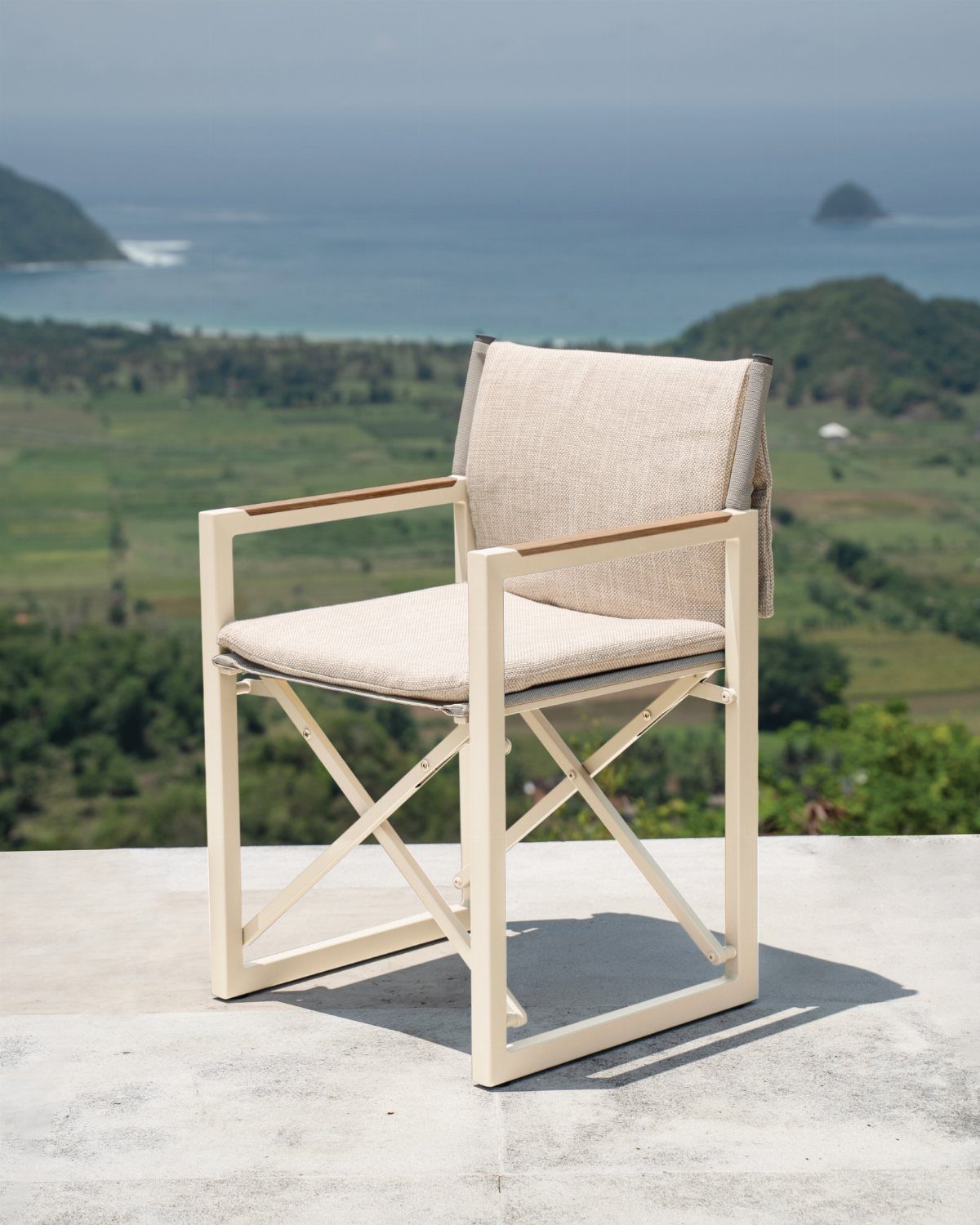 29 Scandinavian Outdoor Furniture for Patios and Gardens 19 Minimalist outdoor armchair with cream frame and beige fabric on a scenic terrace.