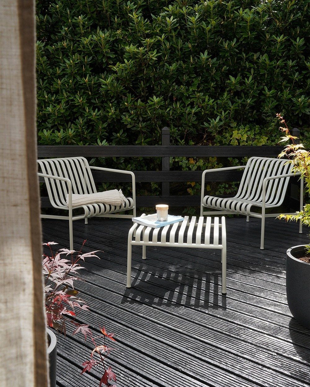 29 Scandinavian Outdoor Furniture for Patios and Gardens 2 Two light metal outdoor armchairs and a matching slatted coffee table on a deck.