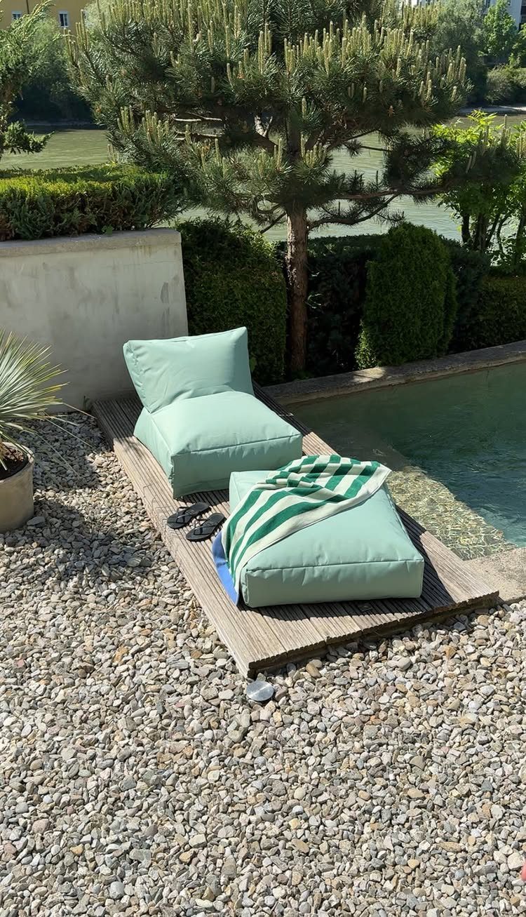 29 Scandinavian Outdoor Furniture for Patios and Gardens 7 Light green outdoor lounge chair with a pillow and blanket by a pool.