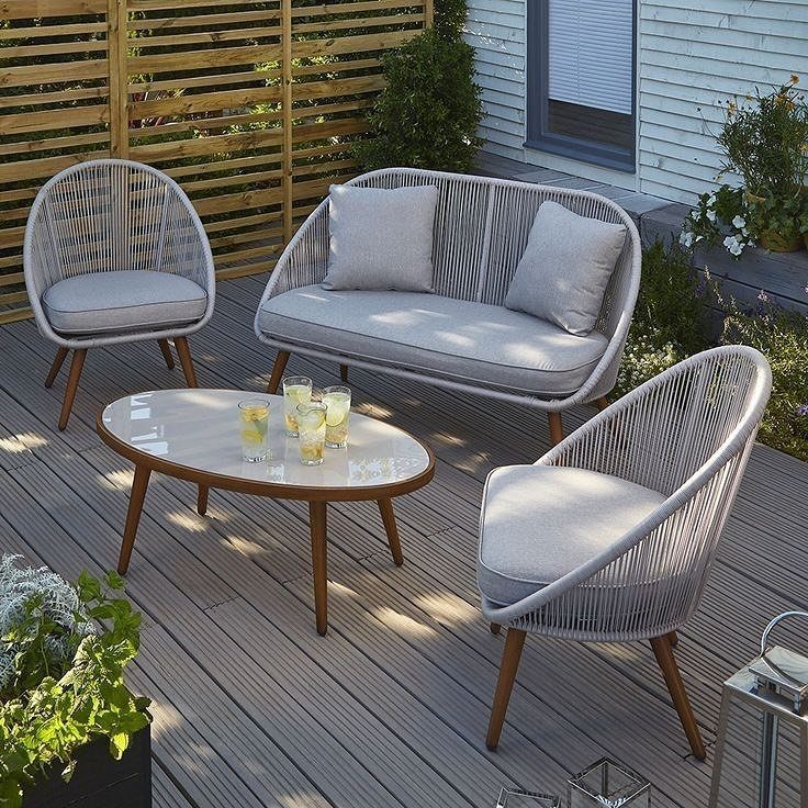 29 Scandinavian Outdoor Furniture for Patios and Gardens 30 Grey rope-woven outdoor sofa and chairs with a glass table on a wooden deck.